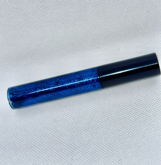 Bottle of Dark Blue holographic Lipgloss styled artistically to the side on clothe light box to highlight the holographic effect of the sparkles and highlight the dark blue